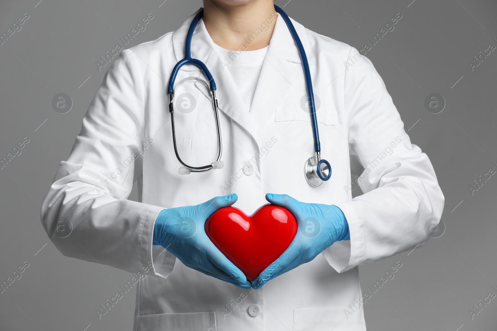 Photo of Doctor with red heart on grey background, closeup