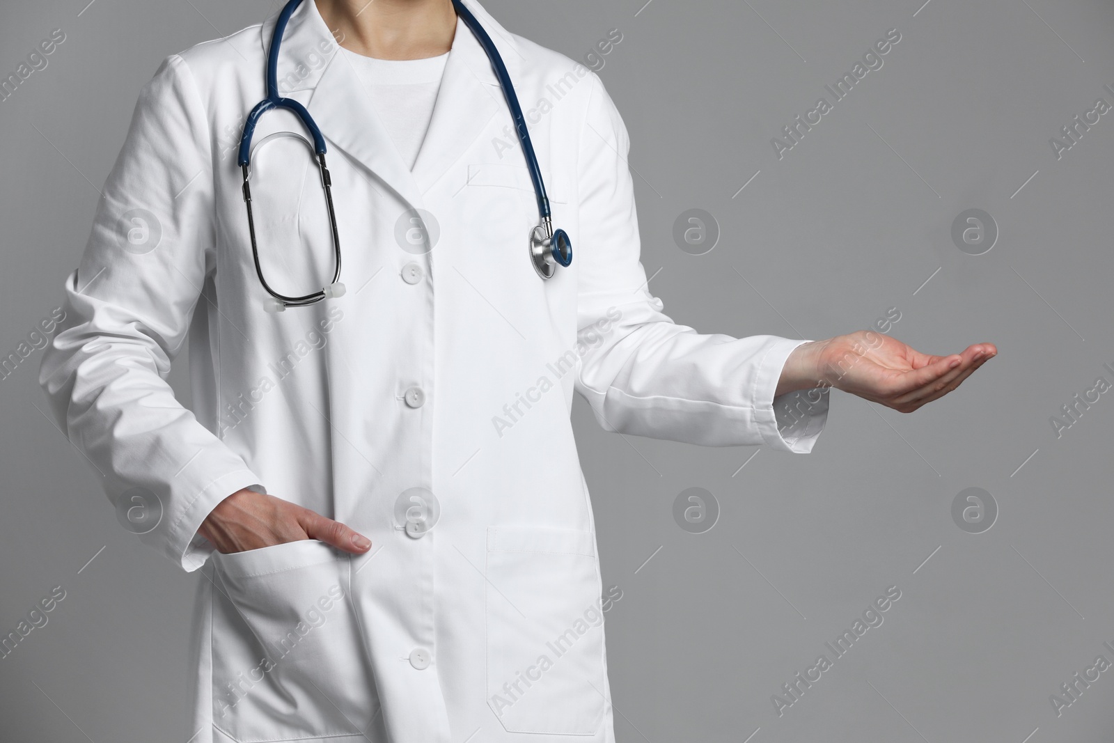 Photo of Doctor holding something on grey background, closeup