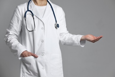 Doctor holding something on grey background, closeup