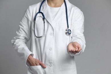 Doctor holding something on grey background, closeup