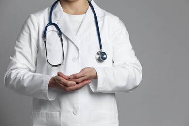 Doctor holding something on grey background, closeup