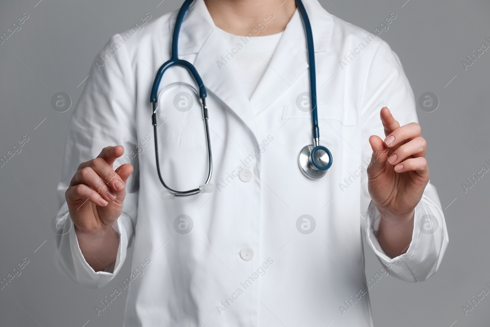 Photo of Doctor holding something on grey background, closeup