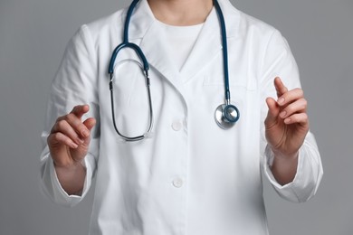 Doctor holding something on grey background, closeup