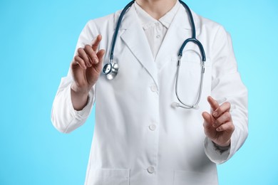 Doctor holding something on light blue background, closeup