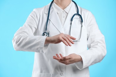 Doctor holding something on light blue background, closeup