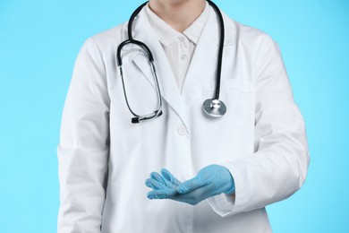 Doctor holding something on light blue background, closeup