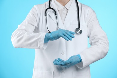 Photo of Doctor holding something on light blue background, closeup