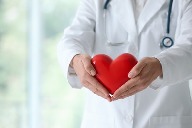 Photo of Doctor with red heart in clinic, closeup. Space for text