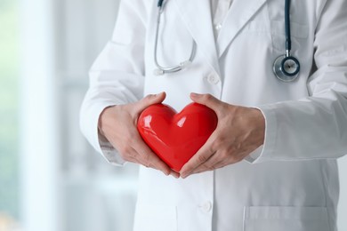 Photo of Doctor with red heart in clinic, closeup