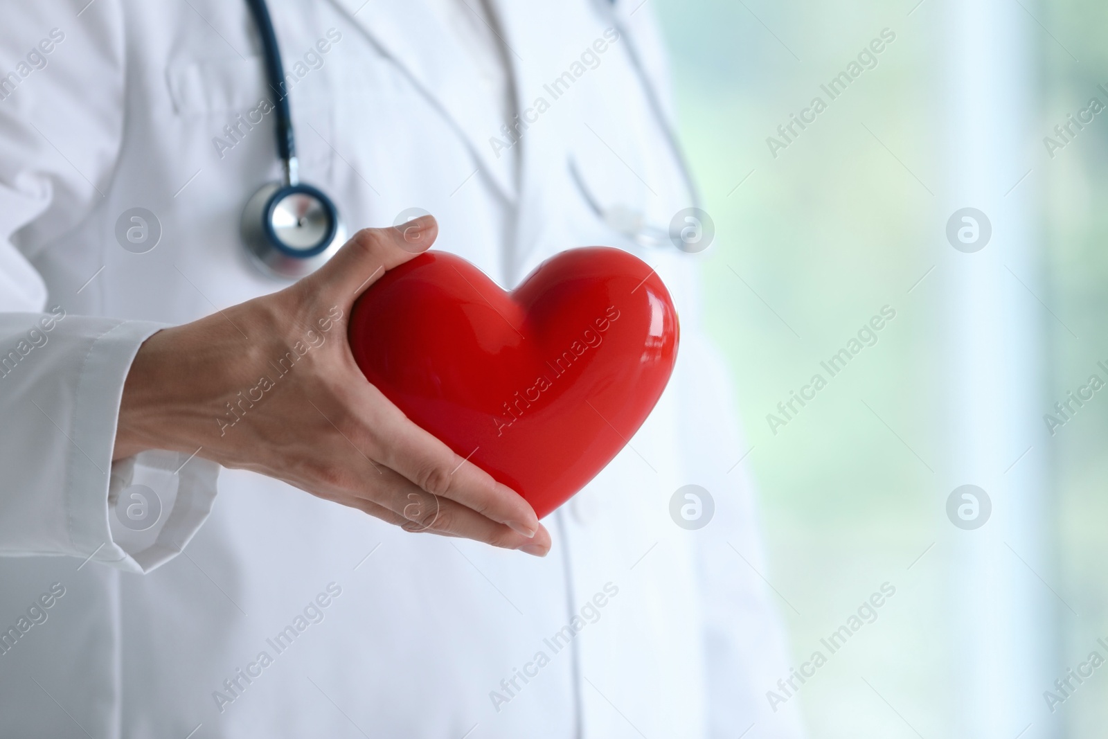 Photo of Doctor with red heart in clinic, closeup. Space for text