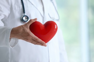 Photo of Doctor with red heart in clinic, closeup. Space for text