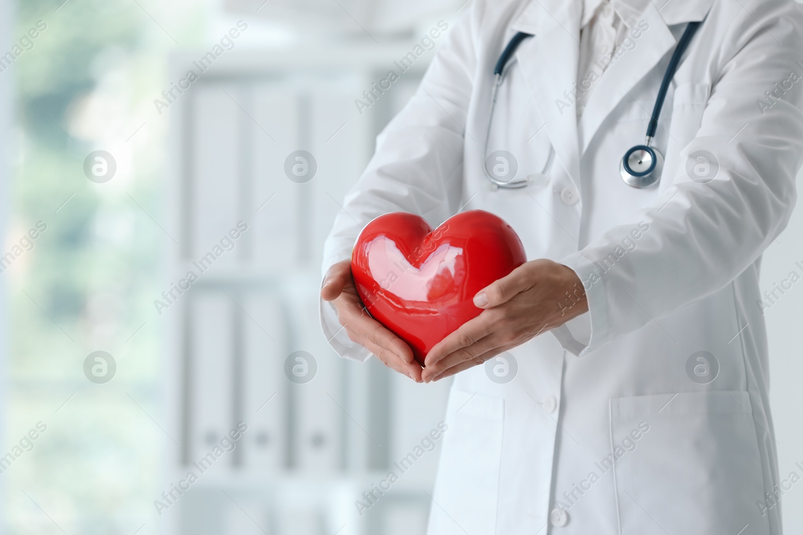 Photo of Doctor with red heart in clinic, closeup. Space for text