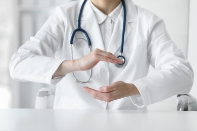 Photo of Doctor with stethoscope holding something at table in clinic, closeup