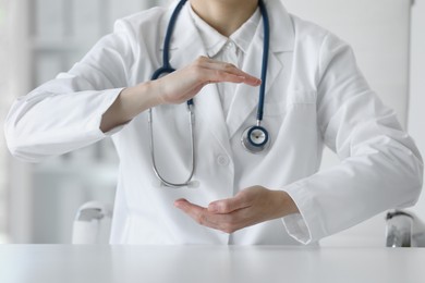 Photo of Doctor with stethoscope holding something at table in clinic, closeup