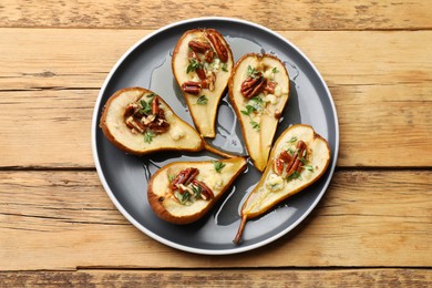 Tasty baked pears with nuts, blue cheese, thyme and honey on wooden table, top view