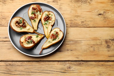 Photo of Tasty baked pears with nuts, blue cheese, thyme and honey on wooden table, top view. Space for text