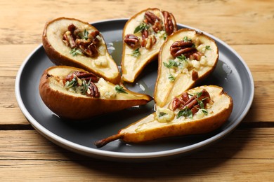 Tasty baked pears with nuts, blue cheese, thyme and honey on wooden table