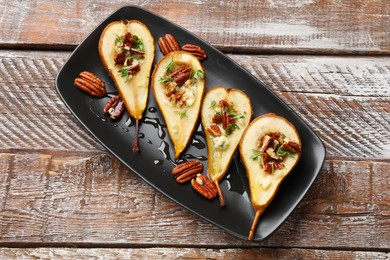 Photo of Tasty baked pears with nuts, blue cheese, thyme and honey on wooden table, top view