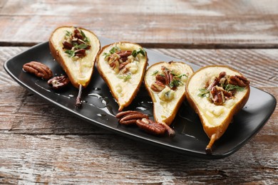 Photo of Tasty baked pears with nuts, blue cheese, thyme and honey on wooden table