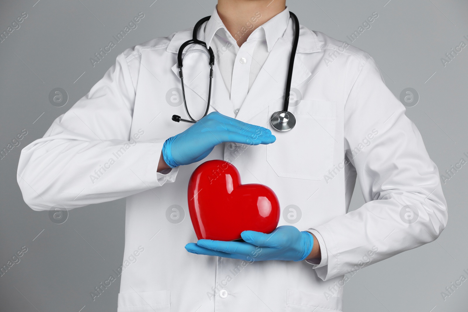 Photo of Doctor with red heart on grey background, closeup