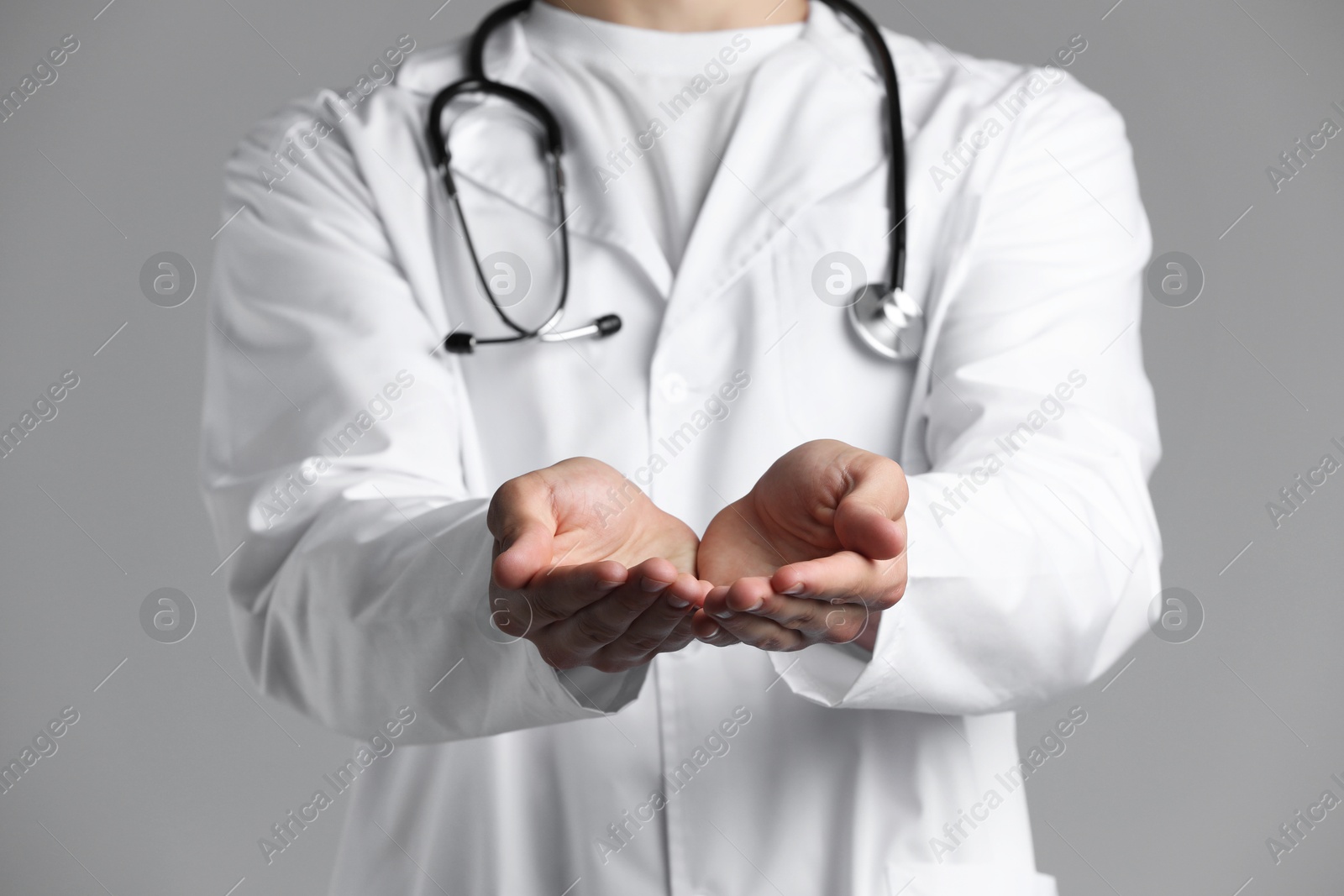 Photo of Doctor holding something on grey background, closeup