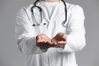 Doctor holding something on grey background, closeup