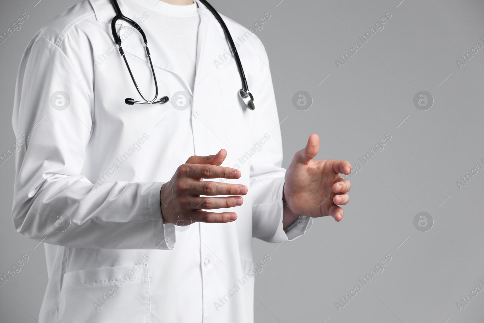 Photo of Doctor holding something on grey background, closeup