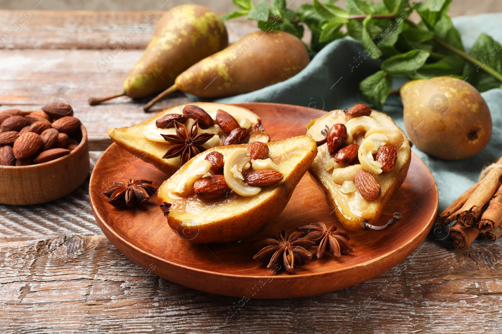 Photo of Delicious baked pears with nuts, anise stars and cinnamon sticks on wooden rustic table, closeup