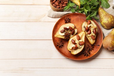 Delicious baked pears with nuts and anise stars on light wooden table, flat lay. Space for text