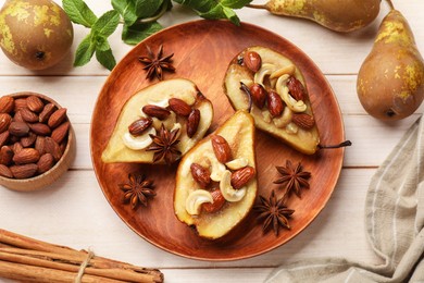 Delicious baked pears with nuts, anise stars and cinnamon sticks on light wooden table, flat lay