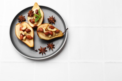 Delicious baked pears with nuts and anise stars on white tiled table, top view. Space for text