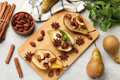 Photo of Delicious baked pears with nuts, mint and anise stars on light textured table, flat lay