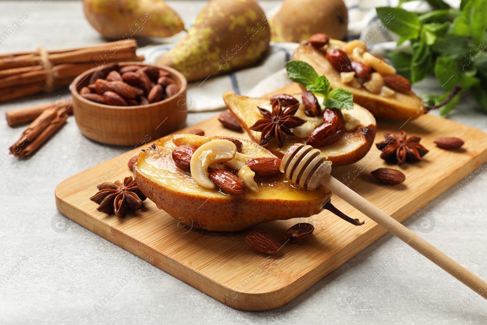 Photo of Delicious baked pears with nuts, honey, dipper and anise stars on light textured table, closeup