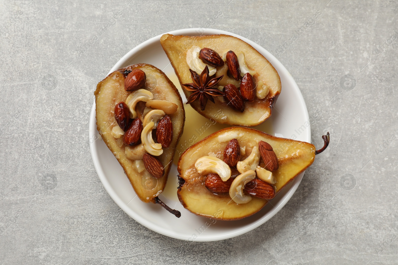 Photo of Delicious baked pears with nuts and honey on grey textured table, top view