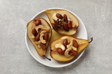 Delicious baked pears with nuts and honey on grey textured table, top view