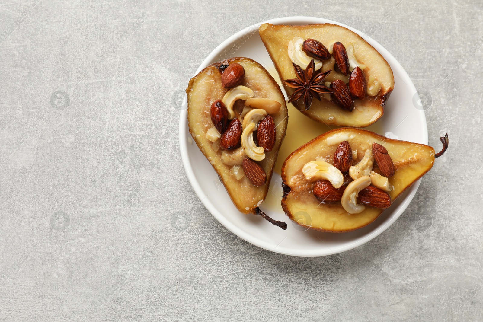 Photo of Delicious baked pears with nuts and honey on grey textured table, top view. Space for text