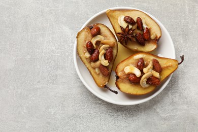 Photo of Delicious baked pears with nuts and honey on grey textured table, top view. Space for text