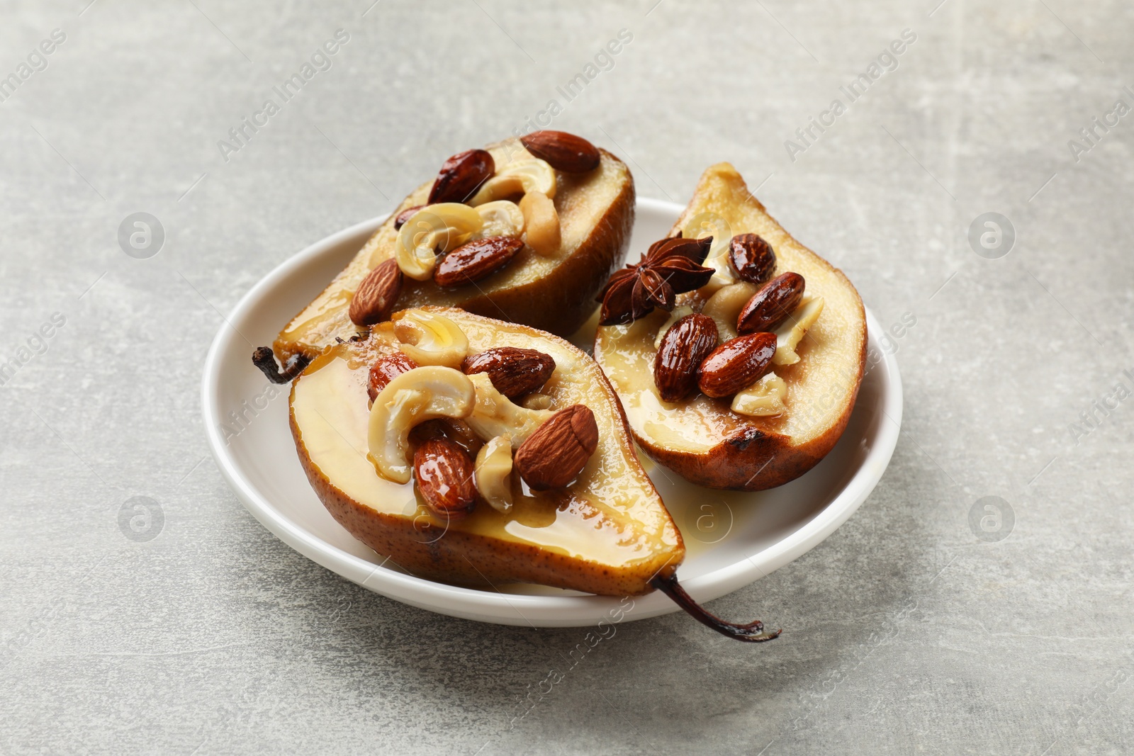 Photo of Delicious baked pears with nuts and honey on grey textured table