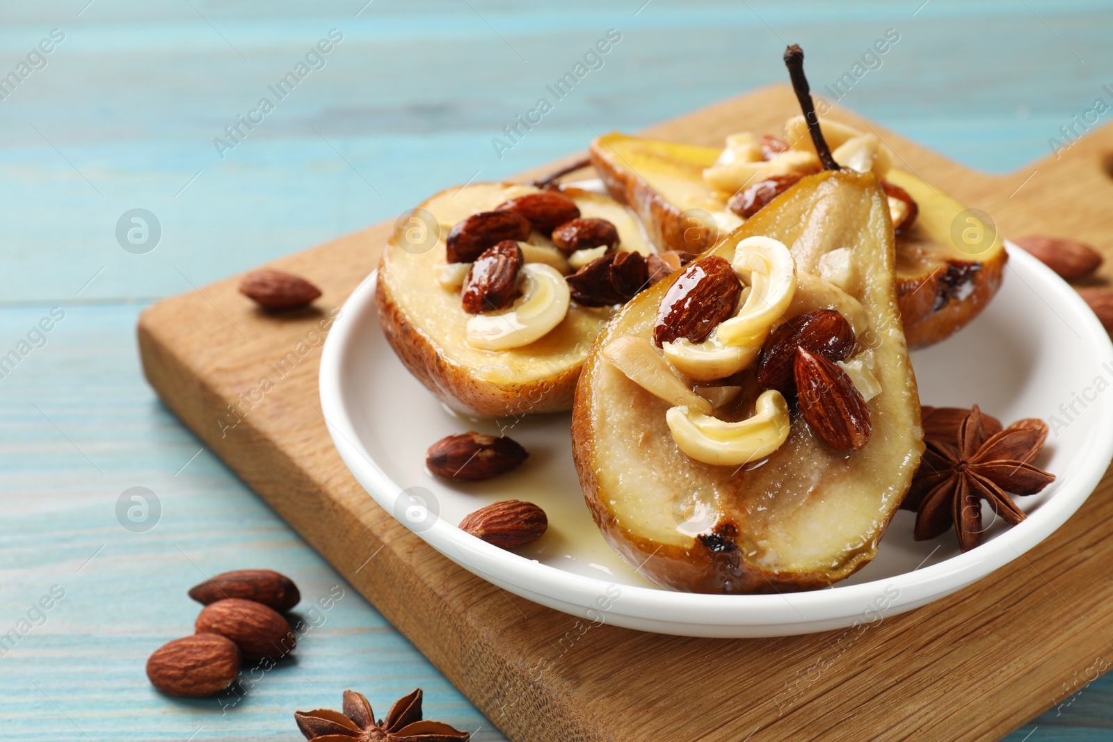 Photo of Delicious baked pears with nuts, anise stars and honey on light blue wooden table, closeup