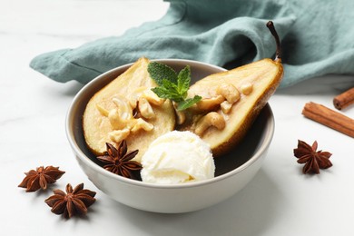 Photo of Delicious baked pears with nuts, ice cream, anise stars, mint and honey in bowl on white table, closeup