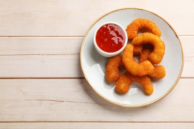 Tasty breaded fried shrimps and sauce on light wooden table, top view. Space for text