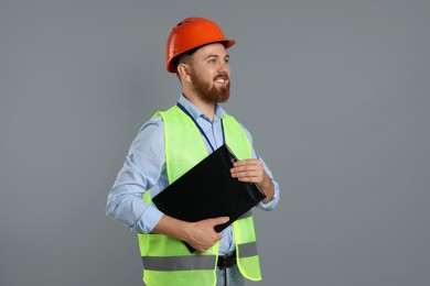 Photo of Engineer in hard hat with clipboard on grey background