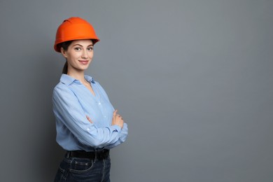 Engineer in hard hat on grey background, space for text