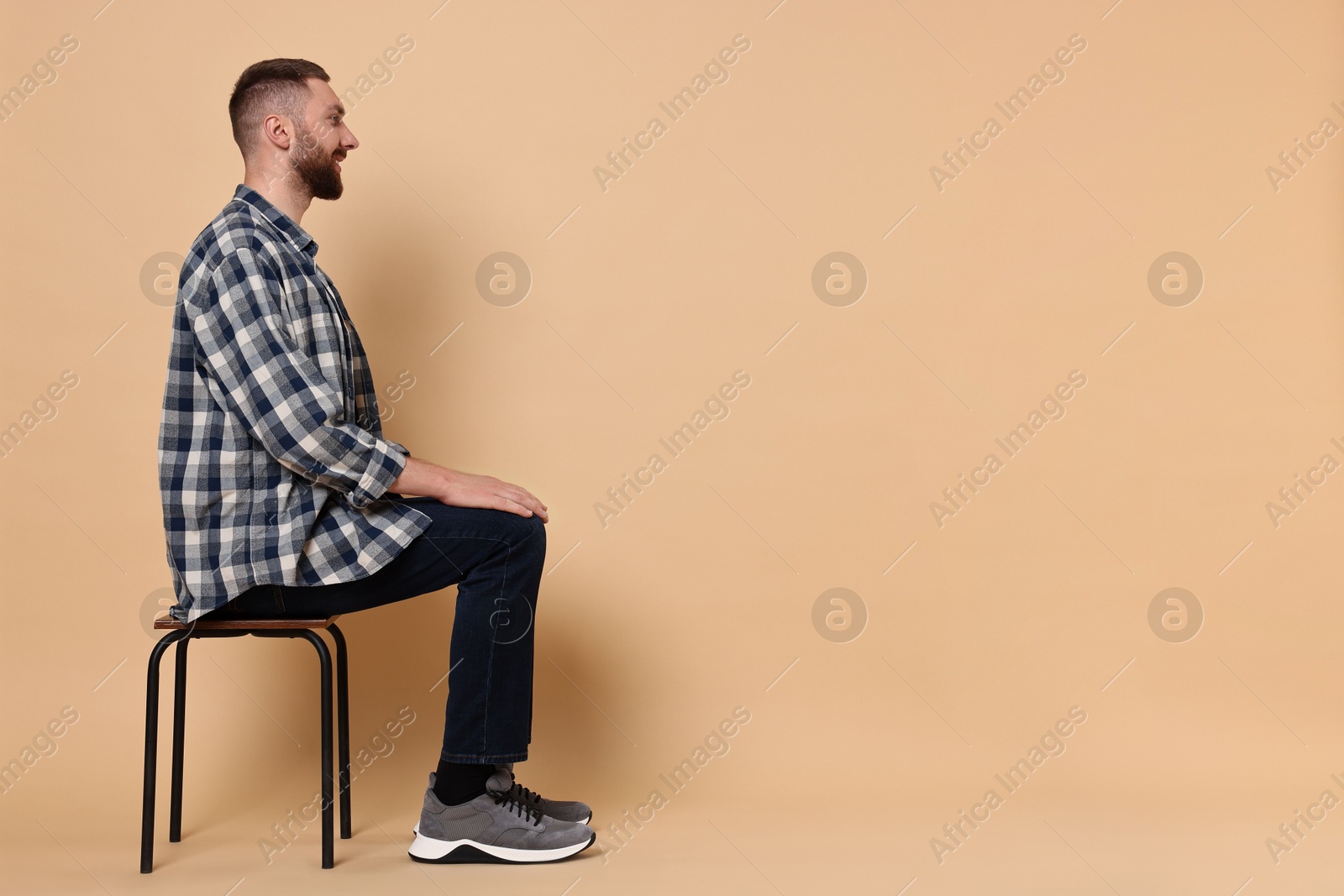 Photo of Man with good posture sitting on chair against pale orange background, space for text