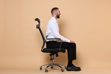Photo of Man with good posture sitting on chair against pale orange background