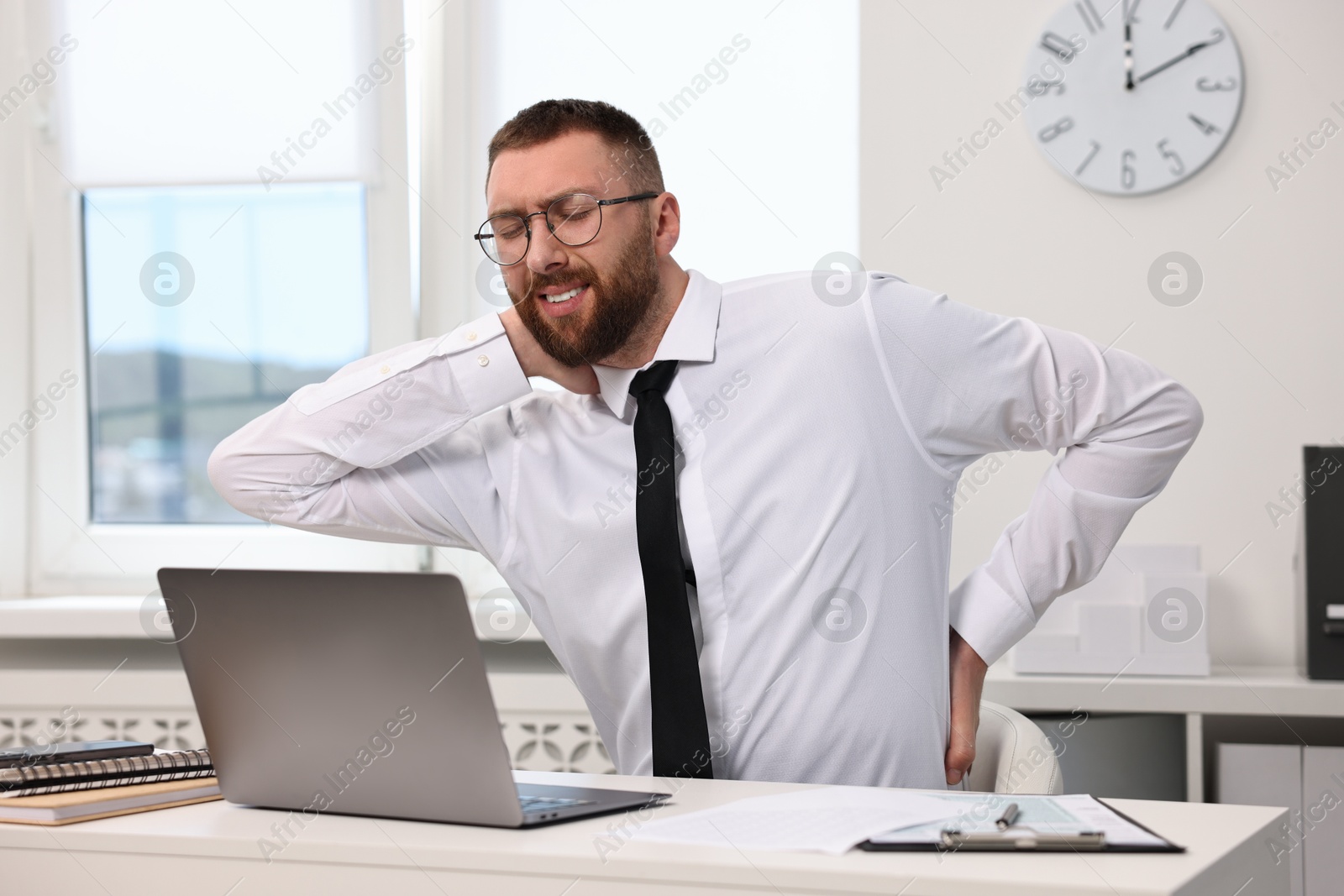 Photo of Man suffering from neck pain in office. Symptom of poor posture