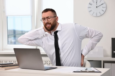 Photo of Man suffering from neck pain in office. Symptom of poor posture