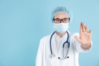 Photo of Doctor touching something on light blue background, selective focus. Space for text