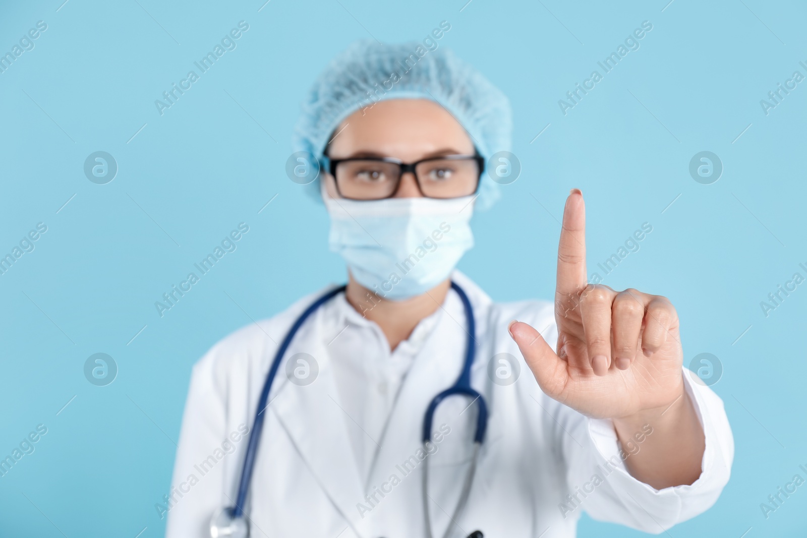 Photo of Doctor pointing at something on light blue background, selective focus