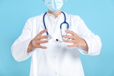 Photo of Doctor holding something on light blue background, closeup